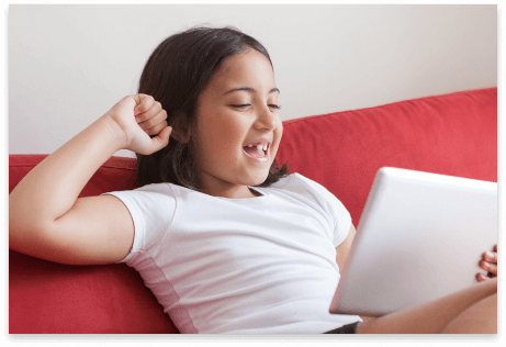 Girl sitting on couch on her tablet smiling